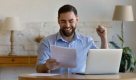Emotional,Laughing,Happy,Young,Man,Looking,At,Paper,Document,,Feeling
